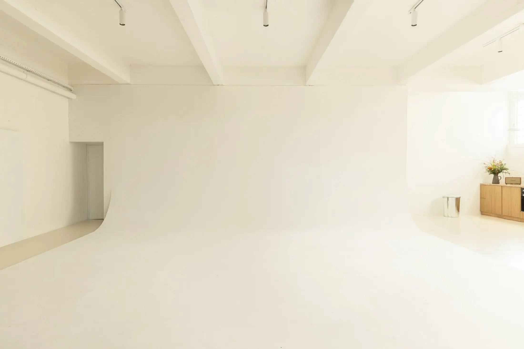 A vast, empty cream studio whose floor curves up seamlessly into the wall.