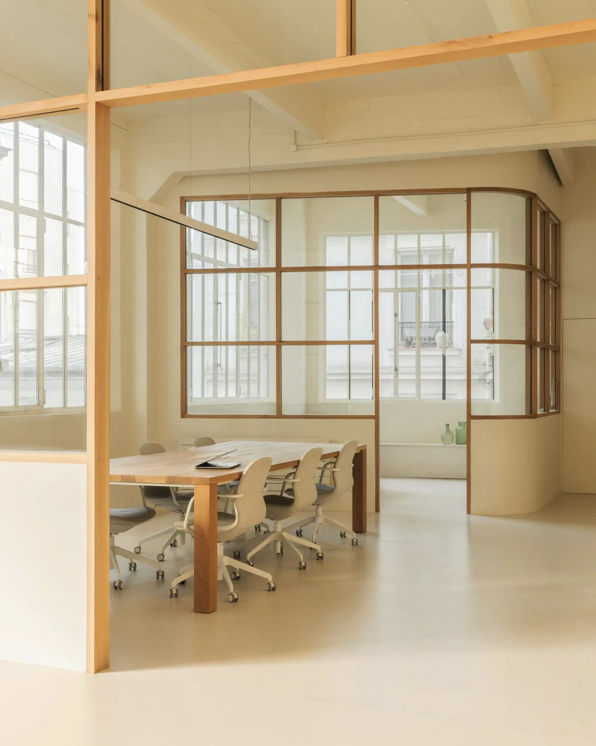 A curved oak-framed glass room containing a long table, seen in warm light.