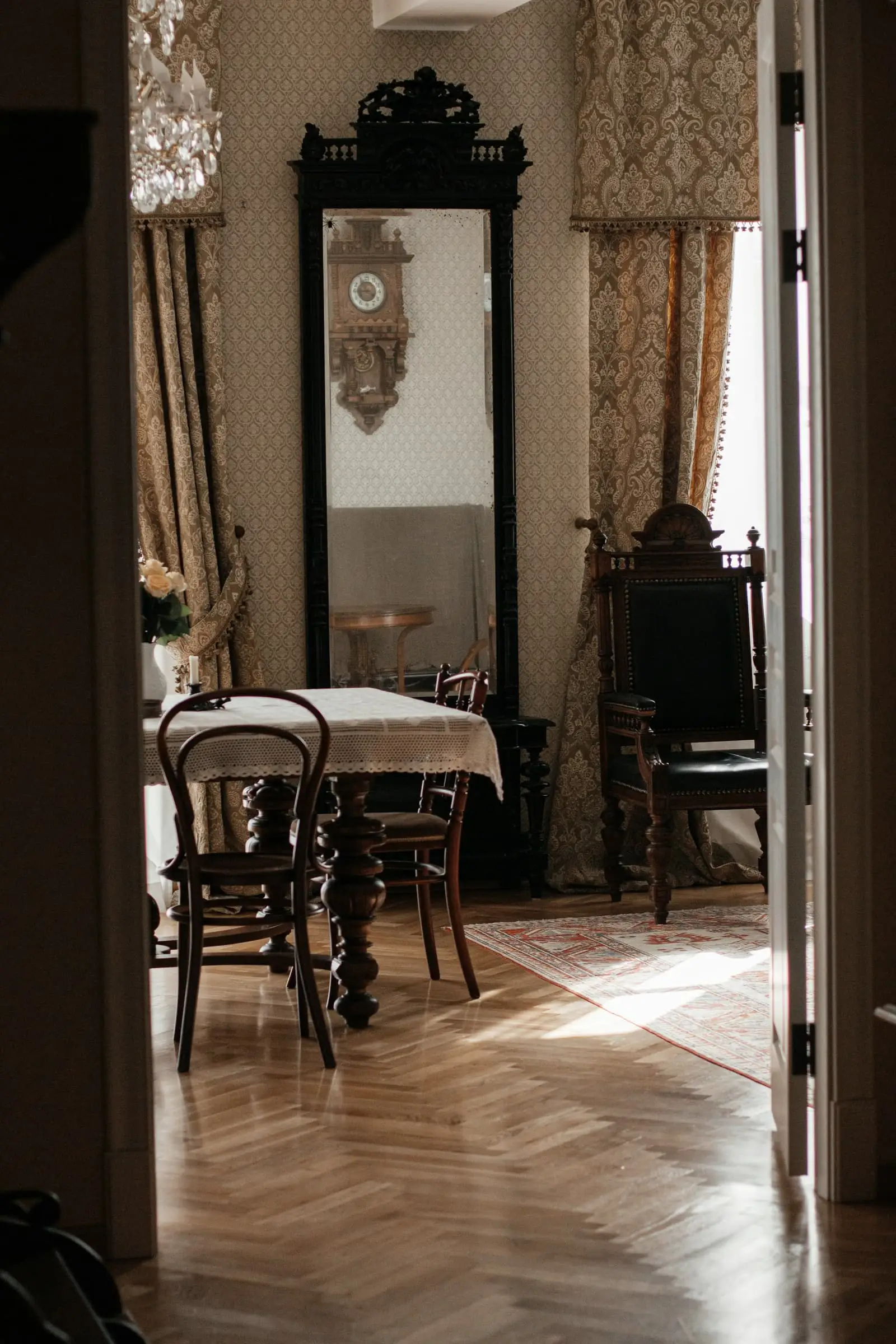A panelled room with antique furniture and a tall mirror, seen through a doorway.