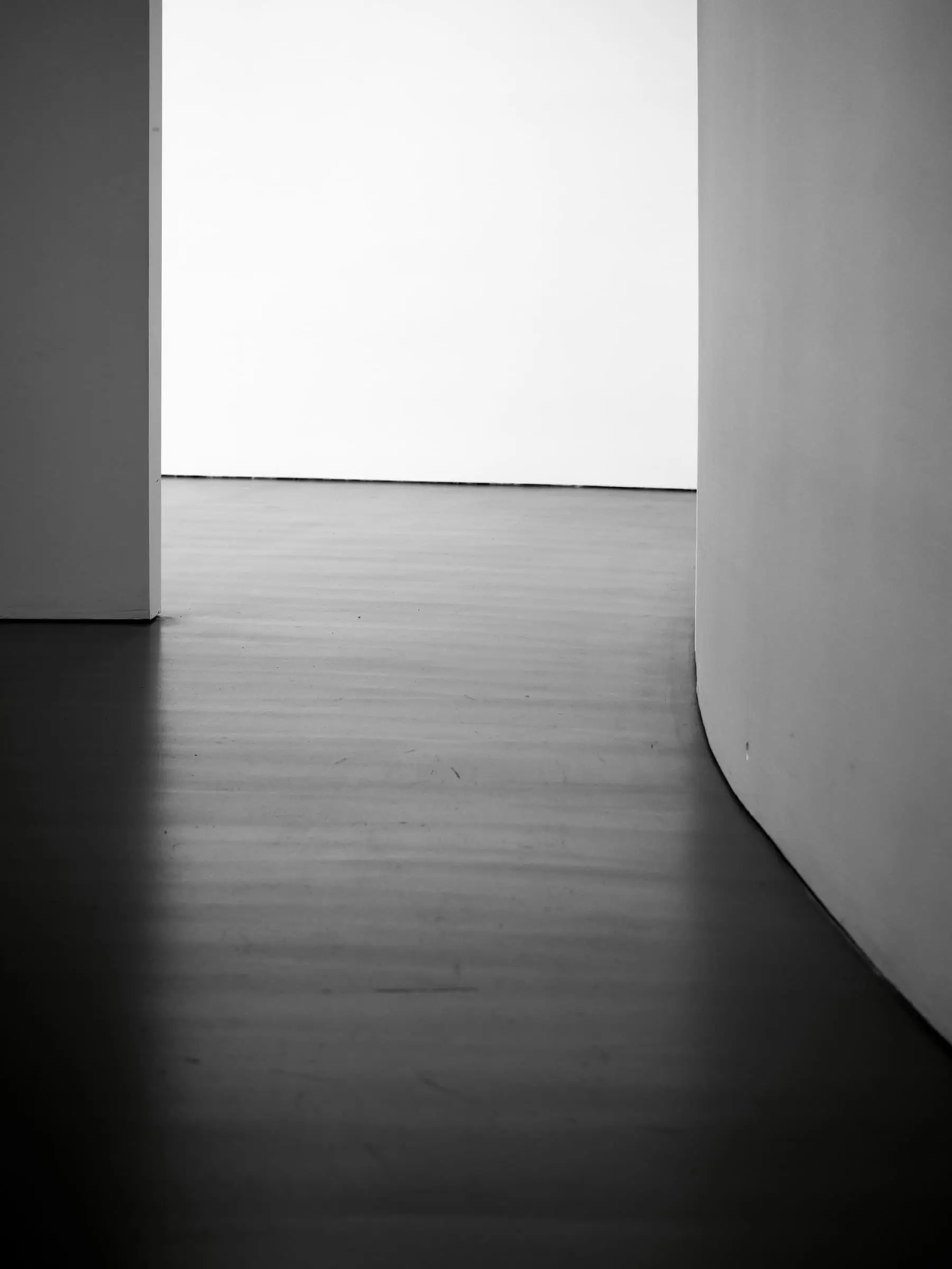 A curved white wall and a very dark, polished floor in strong contrast.