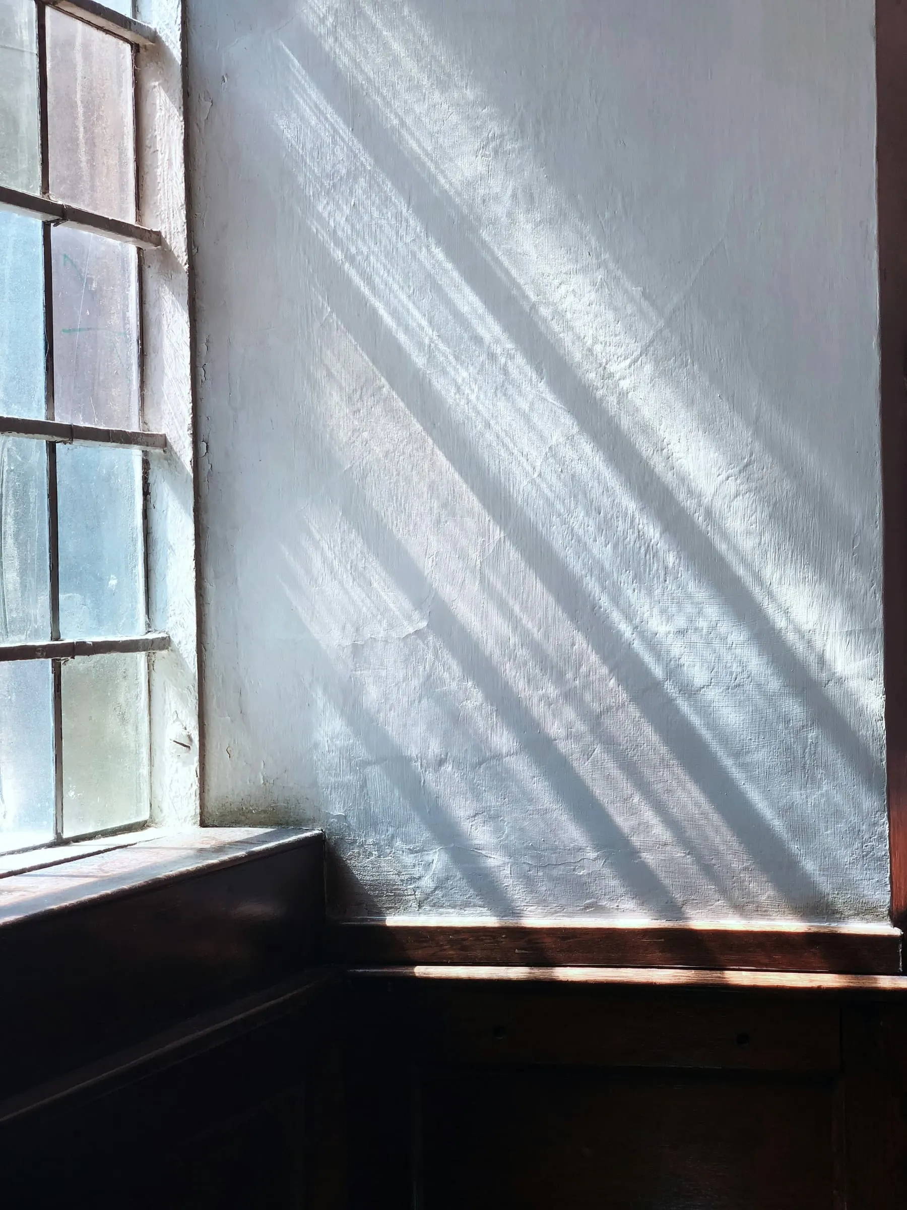 Streaks of light on a blue-white wall beside a tall sash window.