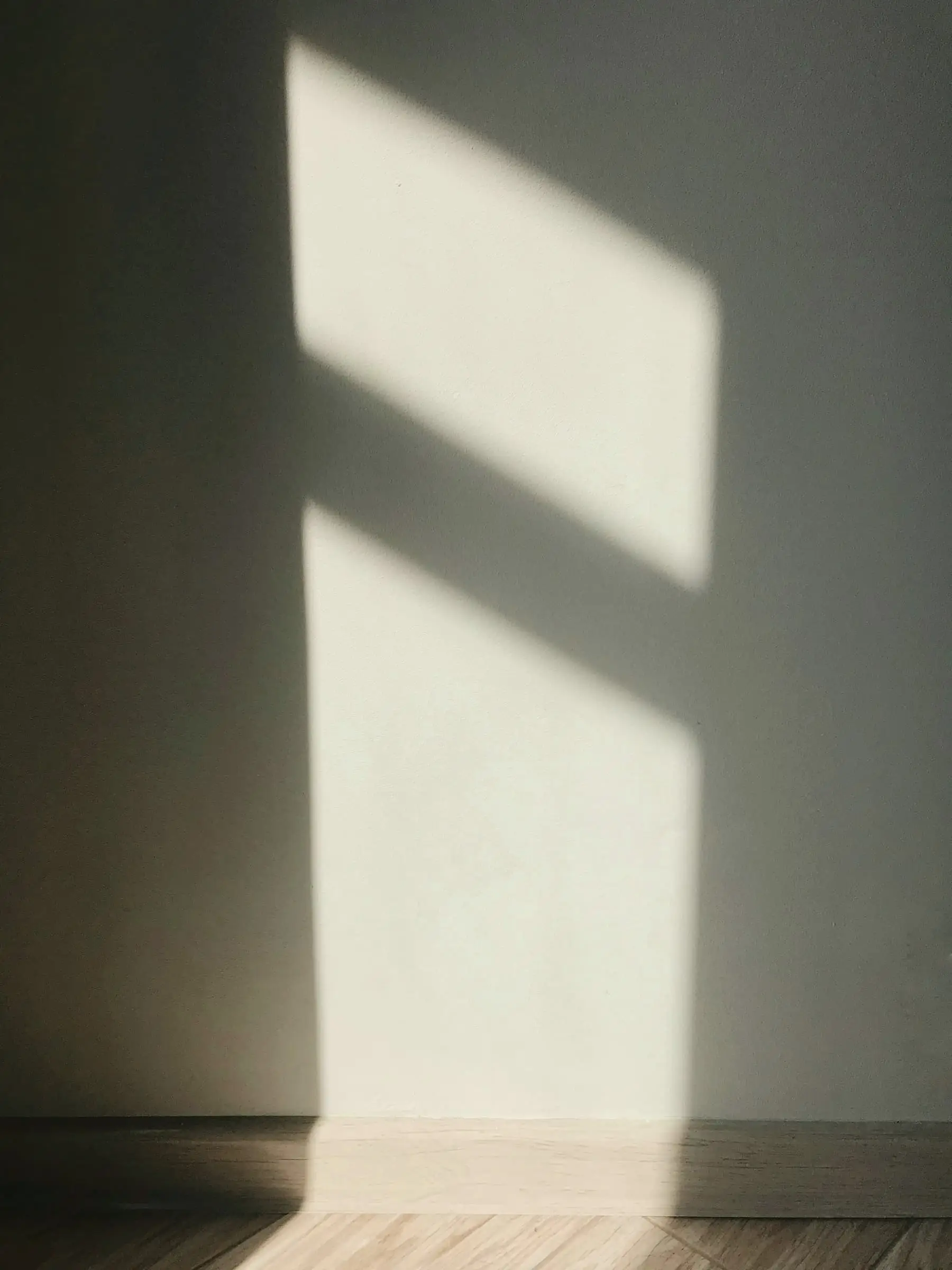 A tall window shadow falling on a pale wall in a dark room.
