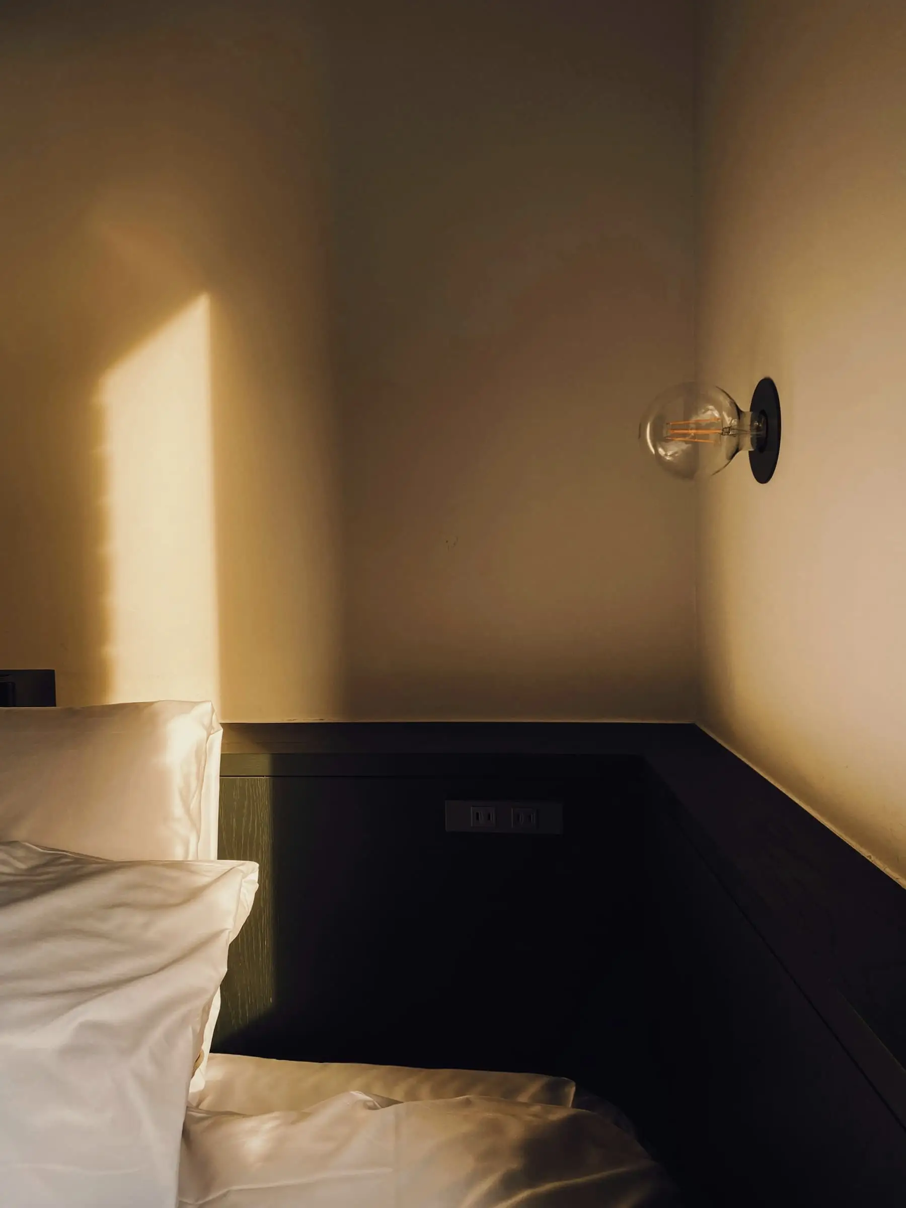An ochre plaster wall in warm light with a wall lamp and a dark timber dado.