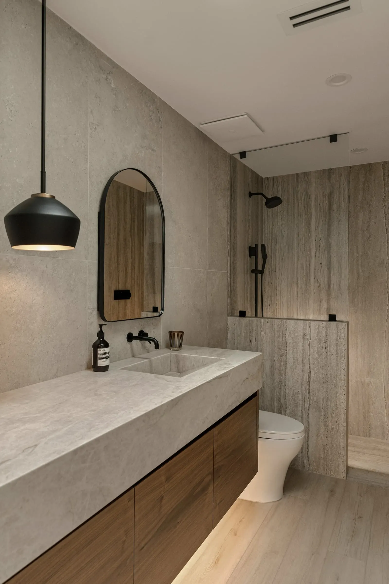 A narrow bathroom with an oak vanity, stone top and timber-effect wall tiles.