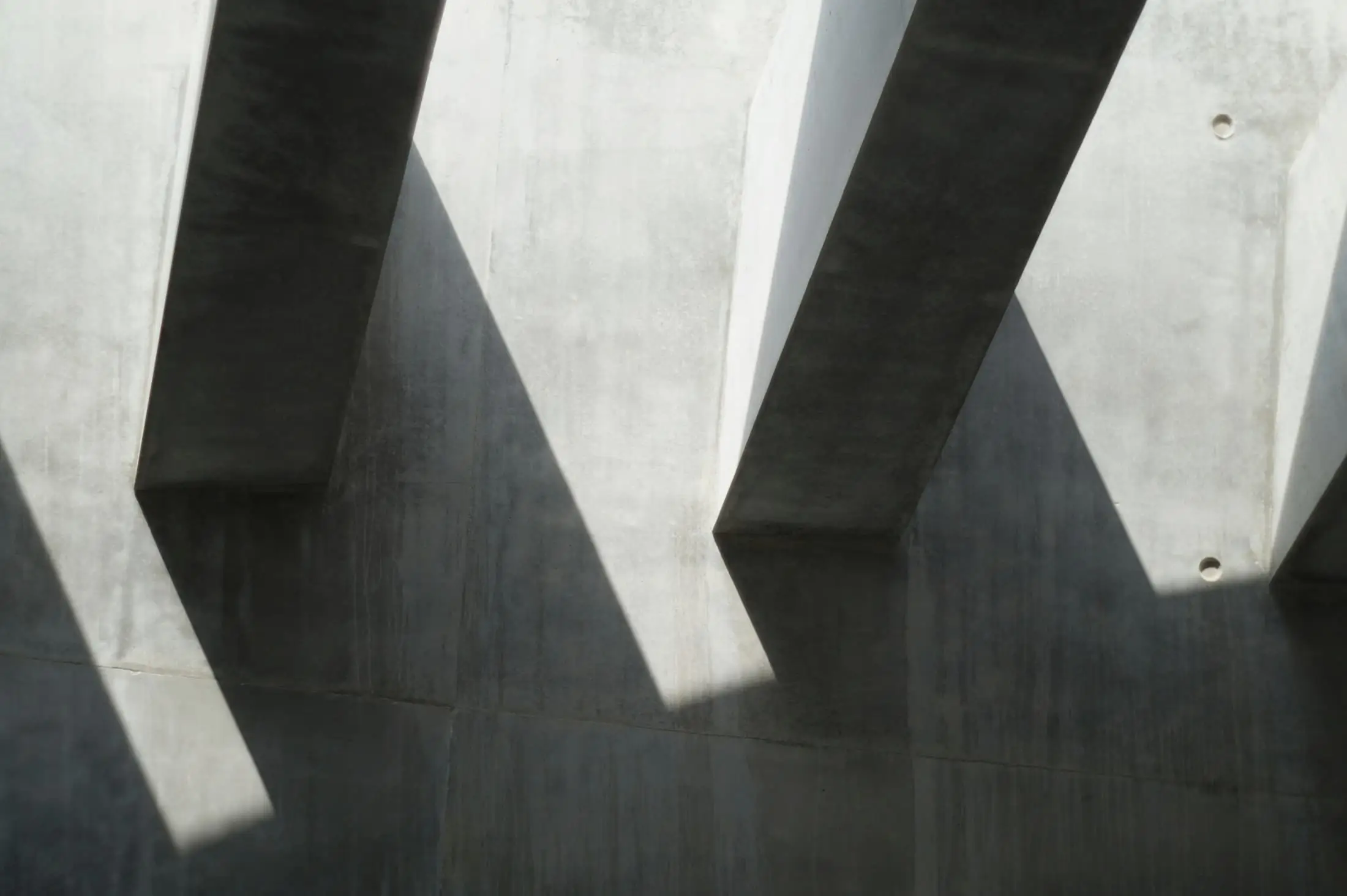 Angled concrete columns casting long shadows on a concrete floor.
