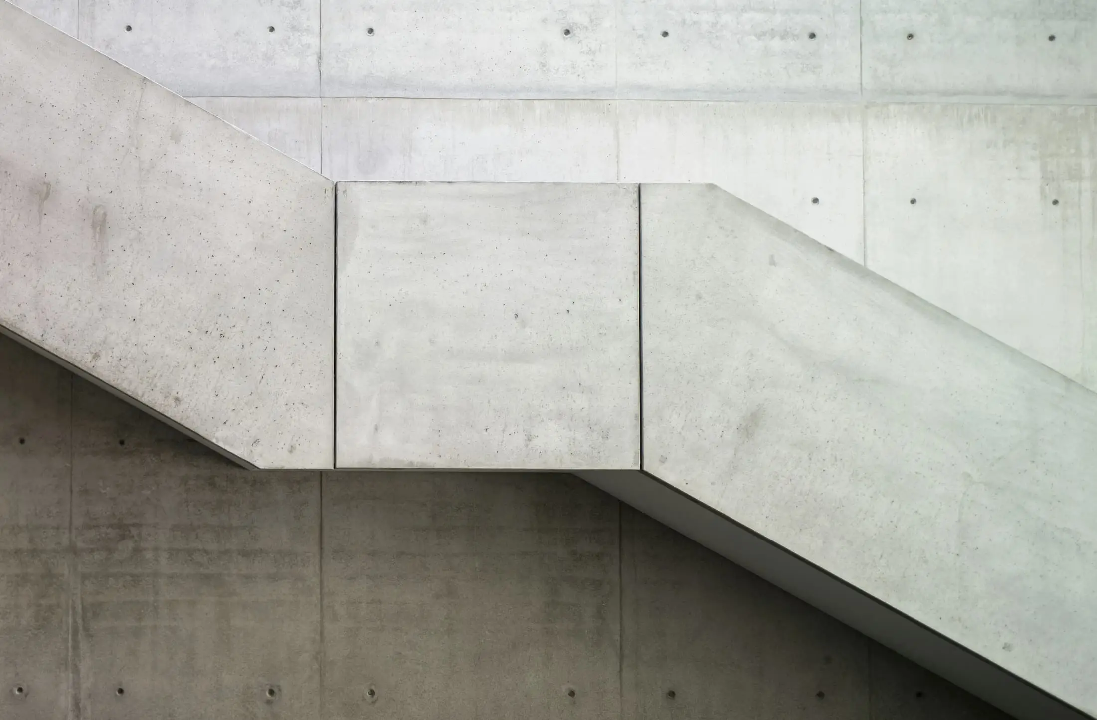 Smooth fair-faced concrete walls and a stair soffit with a regular grid of tie holes.