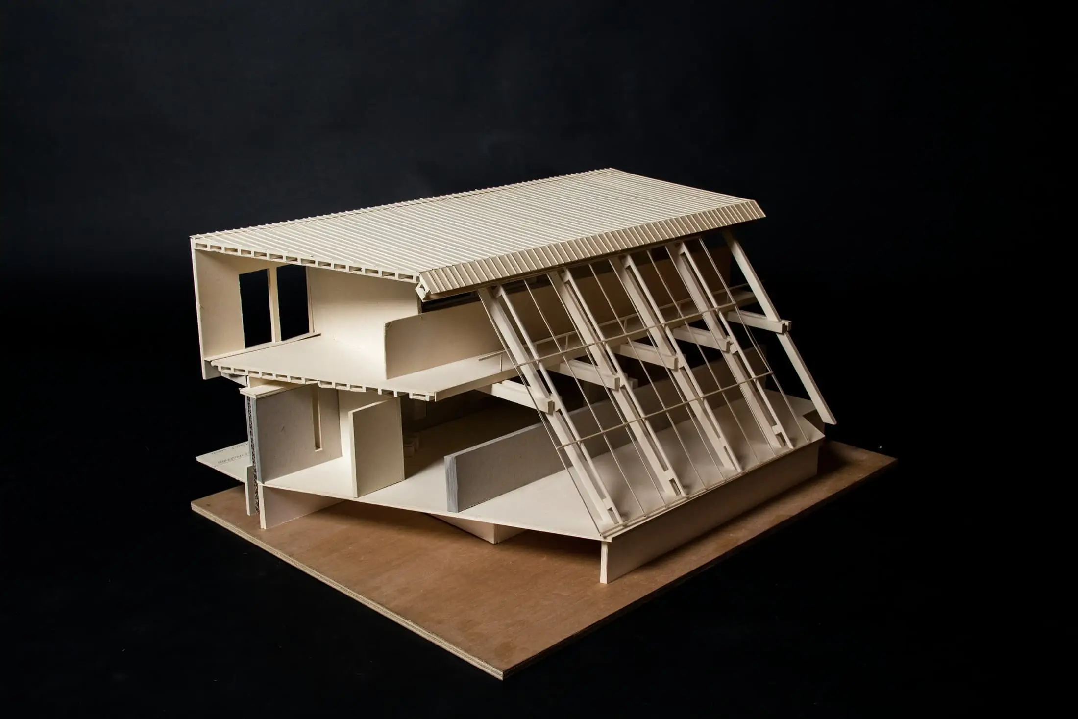 A sectional timber and card model of a stepped house against a black background.
