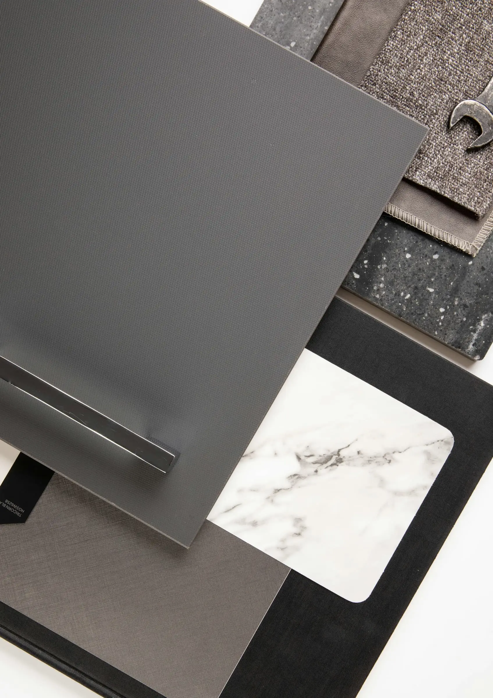 Material samples including grey metal and veined white stone on a pale surface.