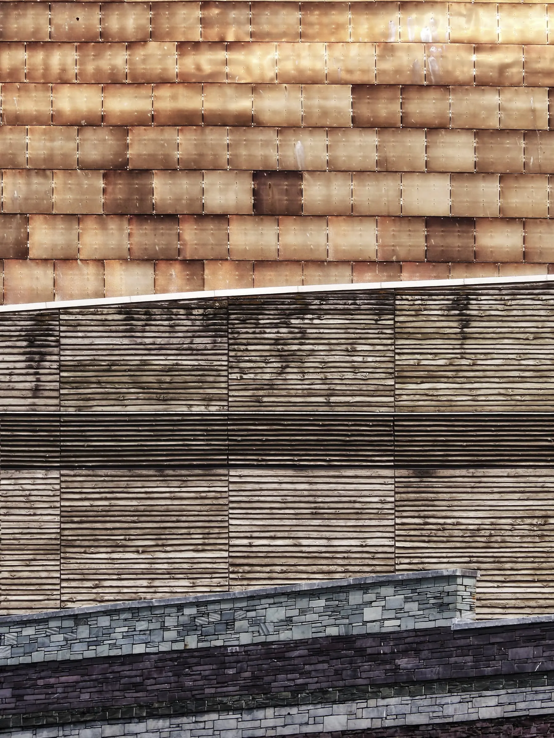 Layered bands of brick, timber and stone samples stacked as a wall.